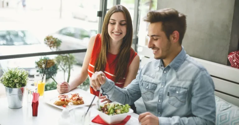 A couple sitting at a cozy outdoor café table, enjoying a fresh and colorful salad together