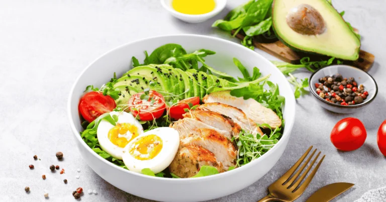 Homemade delicious egg salad served in a bowl with fresh herbs and bread slices on the side.