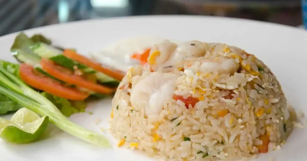 A bowl of vibrant vegetarian fried rice with carrots, peas, and bell peppers.

