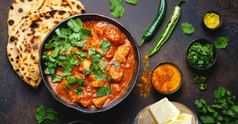 A plate of creamy butter chicken served with naan and rice.