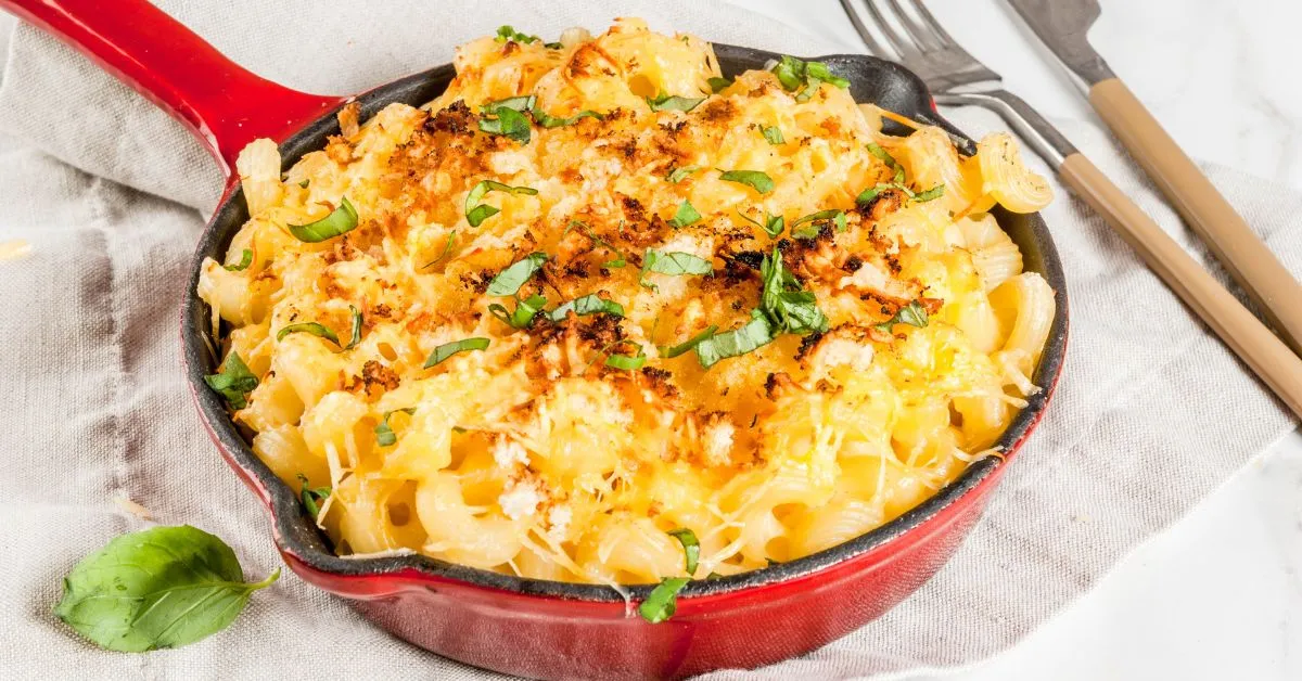 Cheesy buffalo mac and cheese topped with crispy breadcrumbs, served in a skillet with a drizzle of hot sauce.