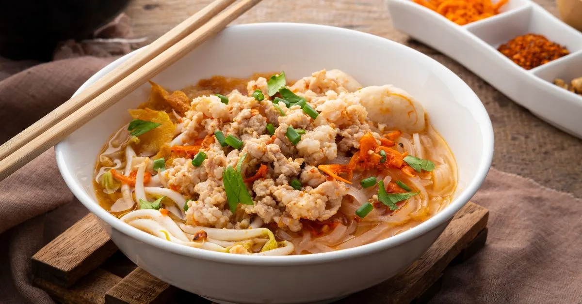 A comforting bowl of chickpea noodle soup filled with vegetables, pasta, and fresh herbs.