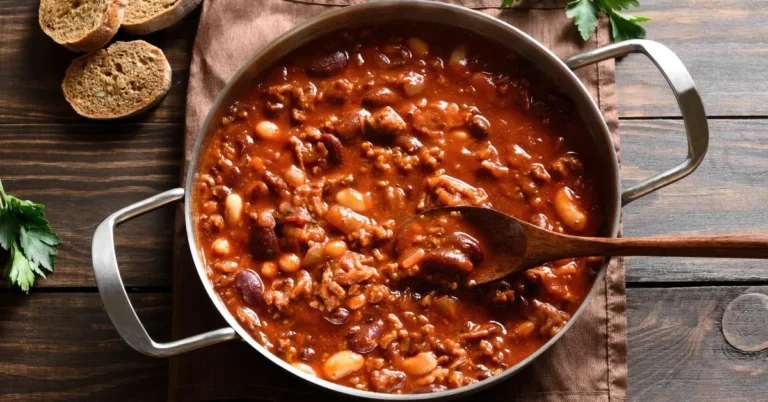 A bowl of delicious beanie weenies with smoky sausages and tender baked beans, garnished with fresh herbs.