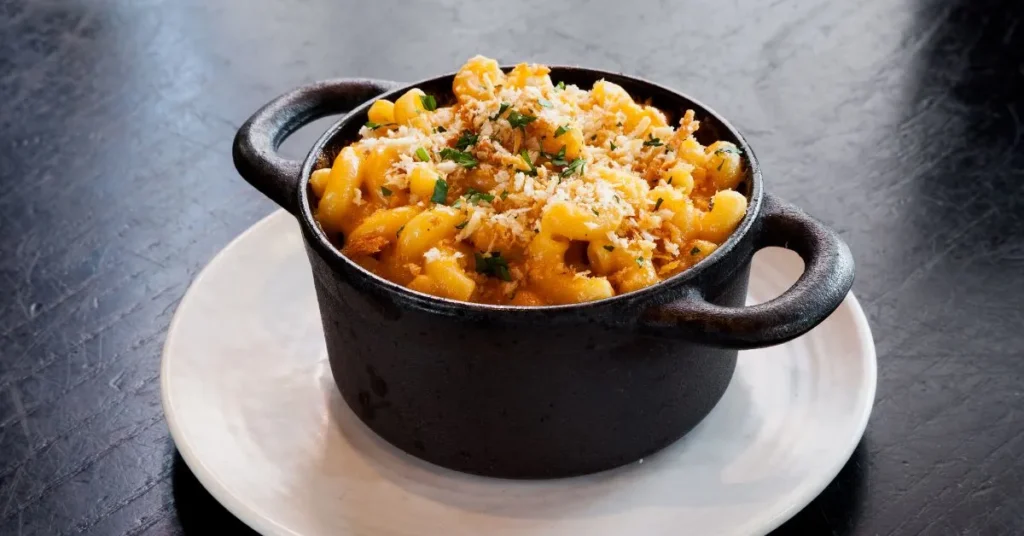 Close-up of creamy buffalo mac and cheese, topped with melted cheddar and breadcrumbs.