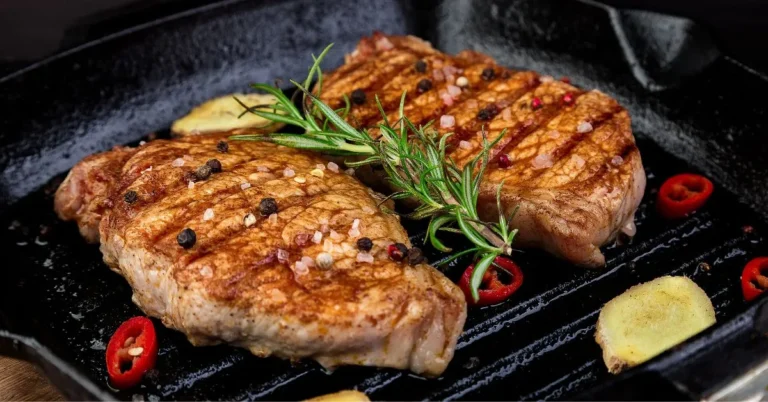 Juicy grilled pork steaks served with herbs and vegetables.