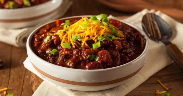 A bowl of hearty homemade vegetarian chili topped with fresh herbs and served with cornbread on the side.