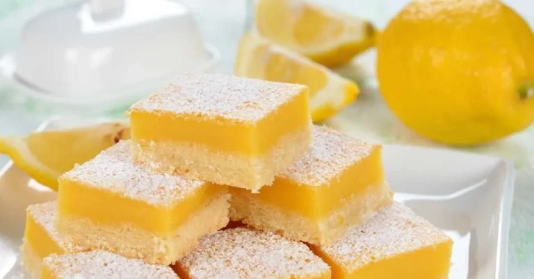 Delicious homemade lemon bars topped with powdered sugar on a white plate.