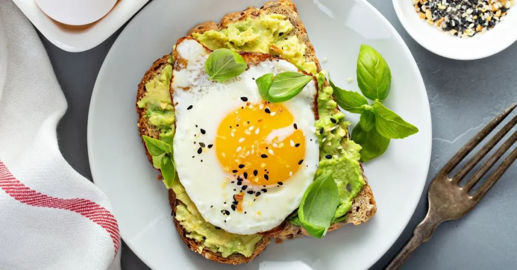 A variety of avocado toasts with different toppings such as eggs, tomatoes, and herbs on toasted bread.