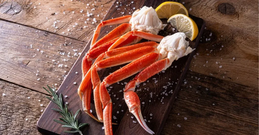 A person cracking open snow crab legs with a seafood cracker to reveal tender meat.