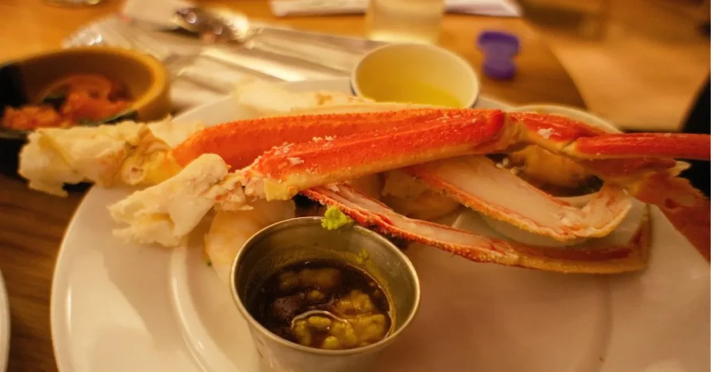 Freshly cooked snow crab legs served on a plate with butter and lemon slices.